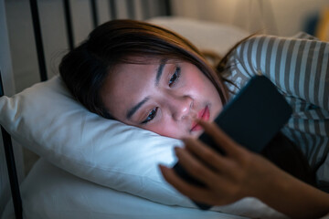 Asian young beautiful woman using mobile phone at night in bedroom. 