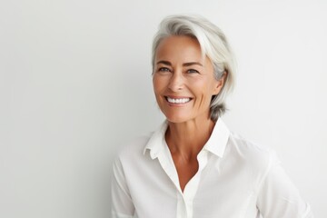 Fototapeta premium Portrait of a smiling senior businesswoman standing against white background.