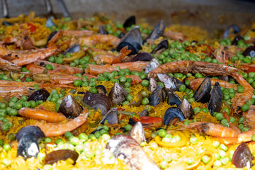 Mexican paella with several ingredients (rice, shrimp, peas, shellfish and tomato) being made in a large wok_2.