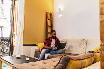 African american man using laptop at home