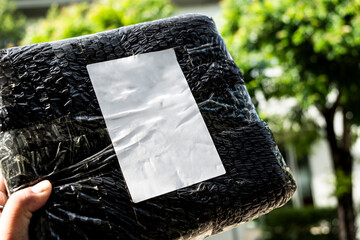 Man holding parcel with black bubble wrapped and empty label. Packaging wrapper product with bubble...