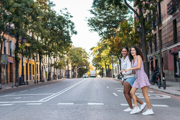 Fototapeta na wymiar Two girls crossing the pedestrian crossing in the city.