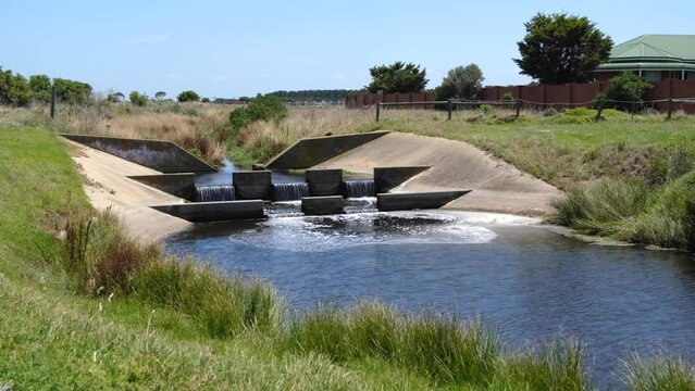 a concrete stormwater drain, where water cascades over steps into a calm retention pond. Concepot of water body management in urban planning. Werribee South, Melbourne Australia