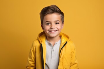 smiling little boy in yellow jacket looking at camera isolated on yellow