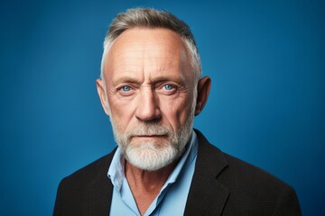 Portrait of a senior man with grey beard. Isolated on blue background.