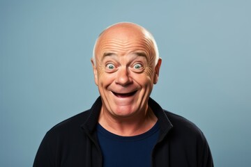 Funny senior man with wide open mouth and surprised expression over blue background
