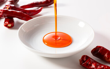Pour chili oil sauce into a ceramic dish. white background.