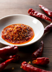 An edible chili oil in a ceramic dish placed on a wooden background.