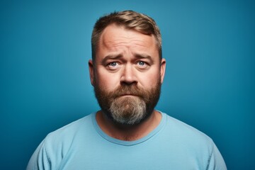 Portrait of a confused man with a beard and mustache on a blue background