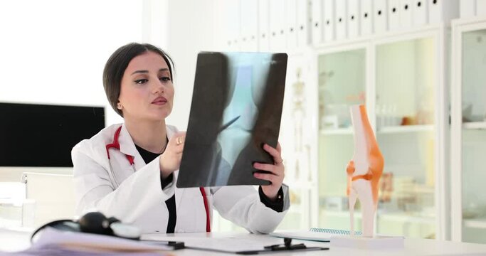 Female traumatologist examines X-ray image of patient leg