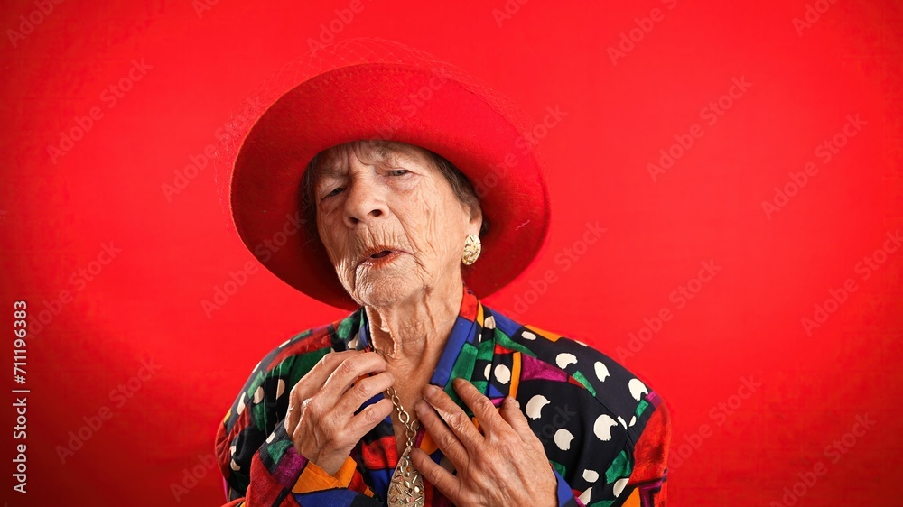 Wall mural closeup funny portrait of happy elderly toothless senior woman wearing red hat pointing fingers hers