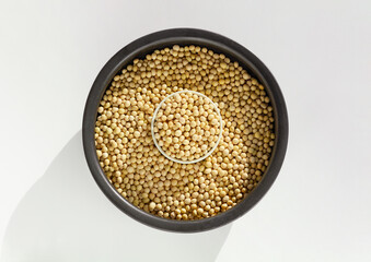 Soybeans in black pottery. Isolated on white background. Top view.
