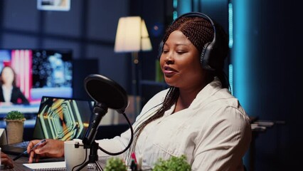 Guest on online podcast show telling interesting story to host, captivating viewers watching during live broadcast. African american woman in studio sharing facts, surrounded by audio tech