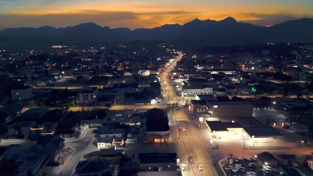 Time lapse da cidade de Joinville no anoitecer, captado por drone, bairro vila nova, com movimento do transito da cidade, luzes noturnas e a serra dona Francisca.