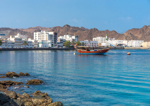 The harbor area in Muscat Oman with a wood boat and the city in the back ground