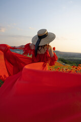 Woman poppy field red dress hat. Happy woman in a long red dress in a beautiful large poppy field....