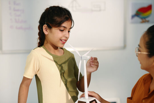 Schoolgirl learning how wind turbine works, environment conservation concept