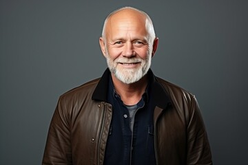 Portrait of a smiling senior man in a leather jacket over grey background.