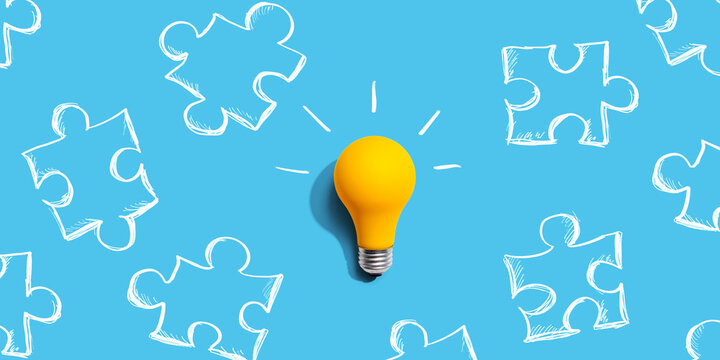 Jigsaw puzzle with a yellow light bulb - flat lay