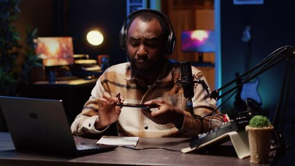 BIPOC tech guru assessing smartphone performance, expressing dissatisfaction with subpar components used. Man shooting mobile phone review for online channel, displeased with low quality materials