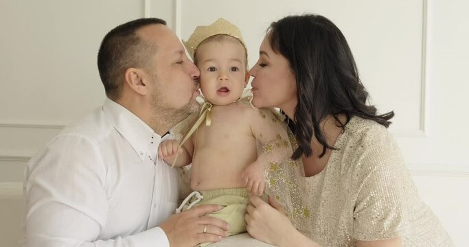 Happy family together. Mother and father kissing their baby on the cheeks. Parenthood, childhood concept