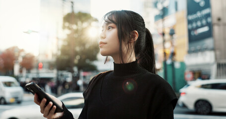 Walking, cellphone and Japanese woman in the city networking on social media or the internet. Phone, adventure and young female person commuting for travel in road of urban town in Kyoto Japan. - obrazy, fototapety, plakaty