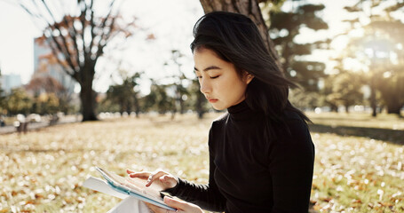 Japanese woman, reading and book on lawn, thinking and relax by tree, park or sunshine with peace. Girl, person or student with story in nature, college or idea with vision, knowledge or campus grass