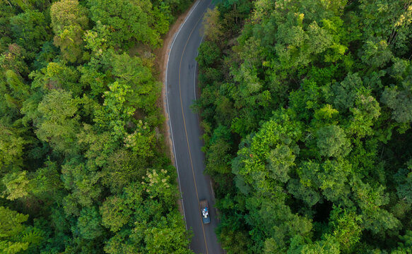 Aerial view of dark green forest road and white electric car Natural landscape and elevated roads Adventure travel and transportation and environmental protection concept © Photo Sesaon