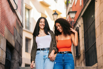 two young women going down street stairs smiling holding her hands
