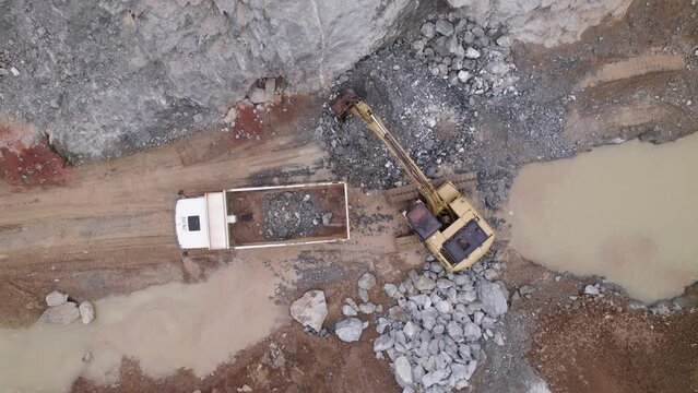 A dynamic drone shot of a excavator which empties its yield into a mining truck