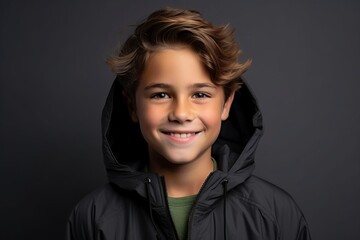Portrait of a smiling little boy in a black jacket on a dark background