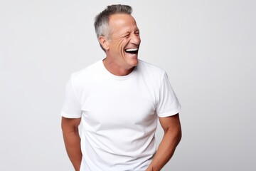 Portrait of a happy senior man laughing while standing against grey background