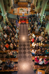 This image provides an aerial perspective of a church congregation during a service. The attendees are arranged in pews, creating a pattern of lines that lead to the altar where a clergy member stands