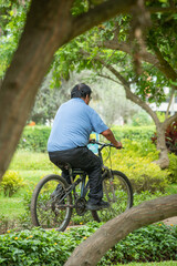 old man on a bike going through a park doing sports