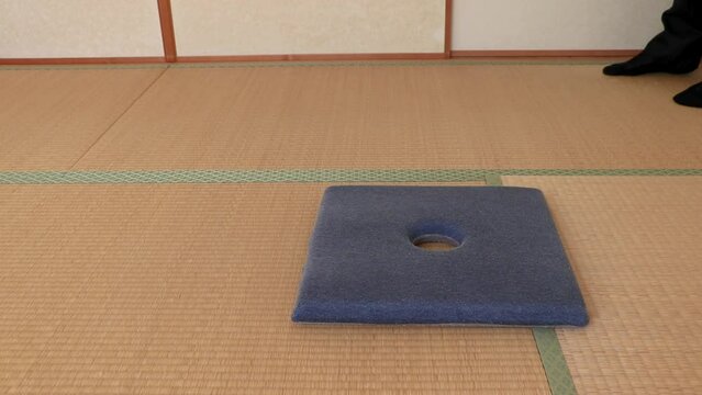 和室に入って座布団の上に正座で座るスーツ姿の男性