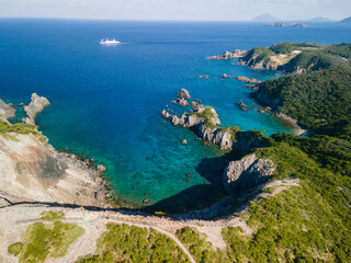 青い海と緑の森が美しい神引展望台から見る、沖を航行する大型客船（さるびあ丸）と中の浦海水浴場、神引浦の空中ドローン撮影。

東京都伊豆諸島新島村式根島にて。
2023年11月4日撮影。

Aerial drone shot of a large passenger ship (Sarubia Maru) sailing offshore, Nakanoura Beach, and Kamihiki