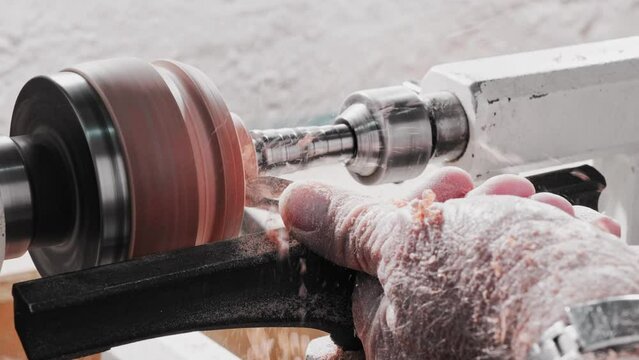 Carpenter using a lathe and chisel to turn a disk of wood