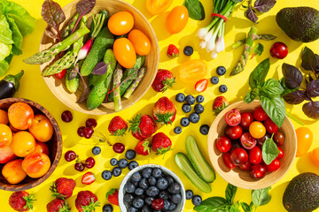 Different berries and vegetables on a bright yellow background. Top view.