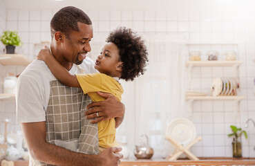 Portrait of little American African black boy parent cooking preparing food with pan in the counter kitchen. Happy family with father son, father's day, healthcare cooking plant based food concept