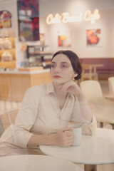 Young Caucasian Female portrait in coffee shop holding a cup of coffee
