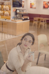 Young Caucasian Female portrait in coffee shop holding a cup of coffee
