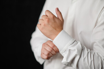 Business man puts on a shirt and adjusts the cuff. Wedding day concept, fashion, business,men...