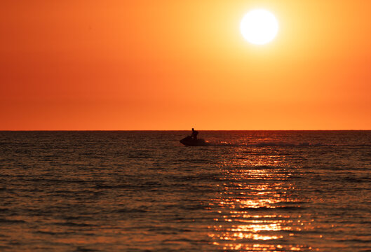 A man on a water scooter rides along the sea. sunset