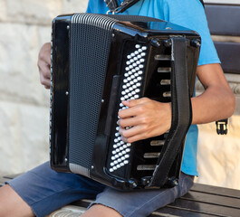 A man plays the accordion while sitting on a bench