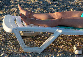 Woman's legs on a sunbed on the beach