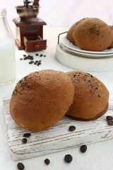 two coffee buns served on a white wooden tray
