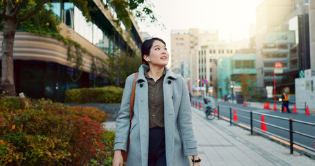 Woman, Asian and walking, travel or commute to work with professional in city with earphones....