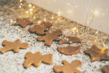 Making traditional Christmas cookies. gingerbread cookies on the kitchen table with holiday lights