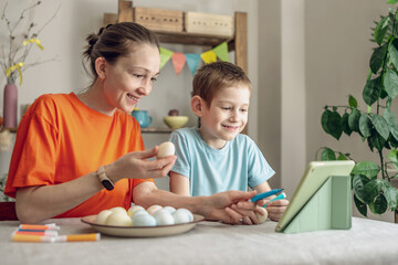 Happy Easter with your family. Mom and son are preparing for spring Easter by cheerfully coloring holiday eggs