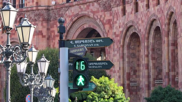 Pedestrian traffic light countdown transitioning from red to green, set against a backdrop of street name signs, lanterns and walls made of red tuf stone, uhd, 4k, 3840, 2160